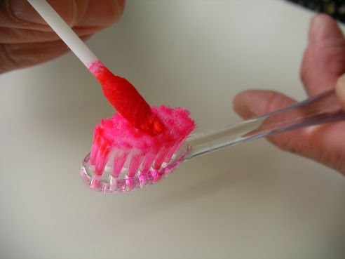 １．アルミパックから歯垢染色液を含ませた綿棒を取り出し、歯ブラシに塗布します。